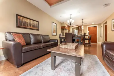 a living room with a leather couch and a table at Solara Suite with Indoor Pool - Hot tub -Parking - GYM in Canmore