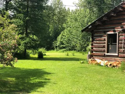an old log cabin in a field of green grass at Mini-Mooh cabin in Clearwater
