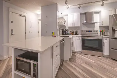 a large kitchen with white cabinets and a counter top at 4 Bedrooms Suite Combo for Group of Families - Windtower Lodge in Canmore