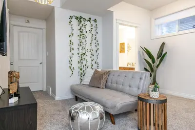 a living room with a couch and a plant on the wall at Bali Style Home - King Bed - Fireplace - Jacuzzi - Fast Wi-Fi - Free Netflix & Garage Parking in Edmonton