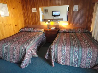 a hotel room with two beds and a television at Airport Inn in Quesnel