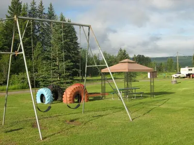 an outdoor park with swings and a picnic table at Airport Inn in Quesnel
