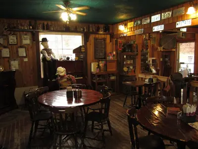 a restaurant with wooden tables and chairs in a room at Old Towne Inne Chuckwagon Bar & Grill in Boston Bar