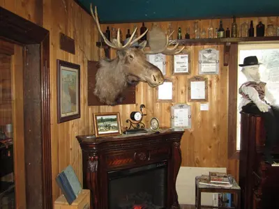 a room with a fireplace and a moose head on the wall at Old Towne Inne Chuckwagon Bar & Grill in Boston Bar