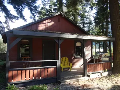 a red cabin with a porch and a yellow chair at Old Towne Inne Chuckwagon Bar & Grill in Boston Bar