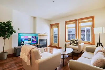 a living room with white furniture and a flat screen tv at Mtn View Escape with King Size Bed with Outdoor Pool - Banff Pass Included! in Canmore