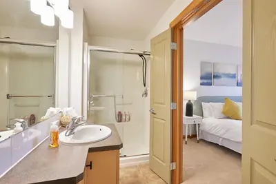 a bathroom with a sink and a shower and a bed at Mtn View Escape with King Size Bed with Outdoor Pool - Banff Pass Included! in Canmore