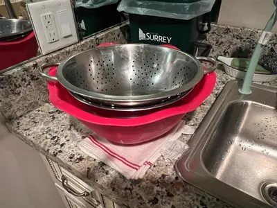 a metal bowl on a red towel next to a sink at Mae Sweet Home in Surrey