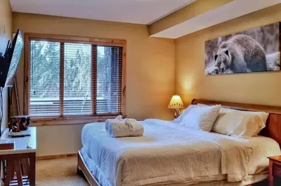 a bedroom with a bed and a picture of a koala at Luxurious Rundle Cliffs Lodge in Spring Creek in Canmore