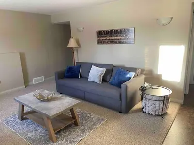 a living room with a blue couch and a table at Spacious Basement suite in Camrose