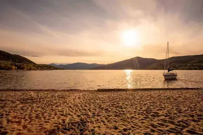 a boat sitting on the shore of a body of water at Top Floor on Okanagan Lake with AC & Heated Pool in Vernon