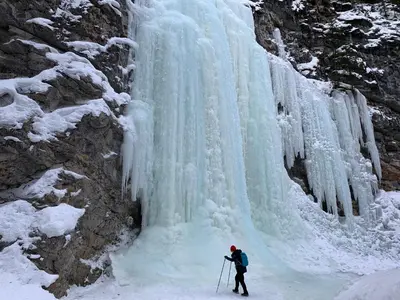 a person is standing in front of a frozen waterfall at Romantic Studio with Kitchen & AC & BBQ & a Huge Balcony 164 in Canmore