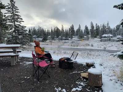 a person sitting in a chair in front of a fire at Romantic Studio with Kitchen & AC & BBQ & a Huge Balcony 164 in Canmore