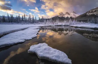 a river covered in snow with a mountain in the background at Romantic Studio with Kitchen & AC & BBQ & a Huge Balcony 164 in Canmore
