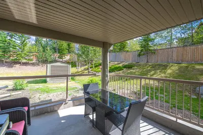 a patio with a table and chairs on a porch at Romantic Studio with Kitchen & AC & BBQ & a Huge Balcony 164 in Canmore