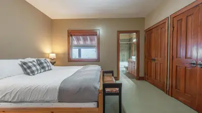 a bedroom with a bed and a window and a door at Mountain Time - Spacious w Private Hot Tub and an Amazing View in Big White