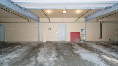 an empty garage with a white door and a ladder at Mountain Time - Spacious w Private Hot Tub and an Amazing View in Big White