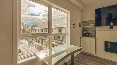 a large window with a view of a city at Skyline Soak - Pool & Hot Tub & Mountain Views in Canmore