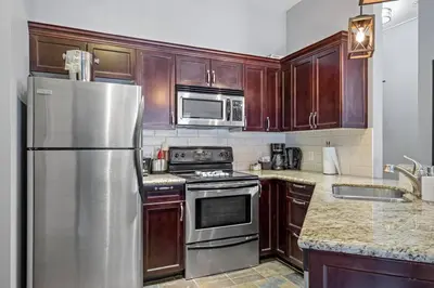 a kitchen with wooden cabinets and a stainless steel refrigerator at Nature's Nook by Instant Suites Pool & HotTub in Canmore