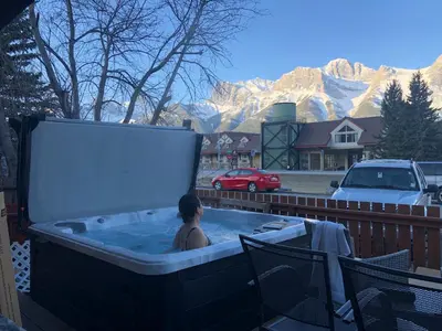 a woman in a hot tub with mountains in the background at Mountain View Escape with Private Hot Tub & Patio in Canmore