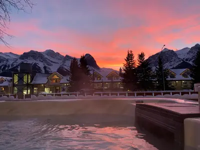 a house with a pool in front of a snow covered mountain at Mountain View Escape with Private Hot Tub & Patio in Canmore