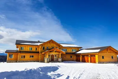 a large wooden house with snow on the ground at Jollymore Ranch in Smithers