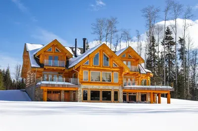 a large wooden house with snow on the ground at Jollymore Ranch in Smithers