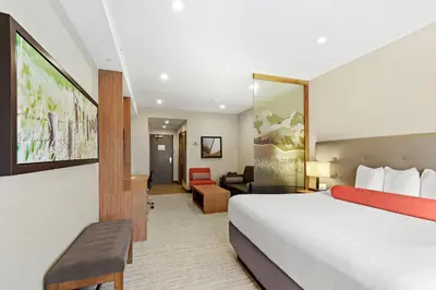 a hotel room with a bed and a living room at Mountain View Inn & Suites in Sundre