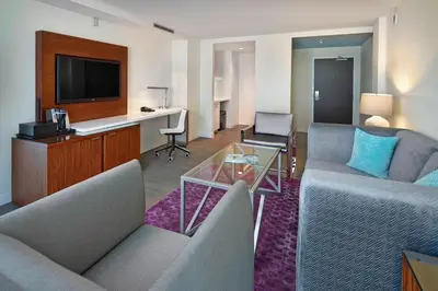 a living room with couches and a desk and a television at Renaissance Edmonton Airport Hotel in Nisku
