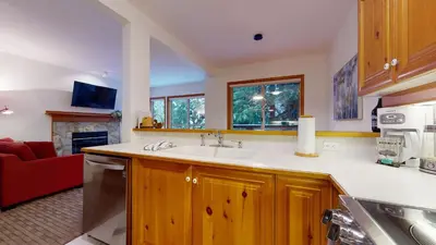 a kitchen with a sink and a red couch at 2BR in Painted Cliff, Ski In, Ski Out, Communal Hot Tub, Wood Burning Fireplace, Free Parking in Whistler