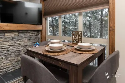 a dining room table with chairs and a television at Heavenly Mountain Hideaway, Pool, Hot Tub in Radium Hot Springs