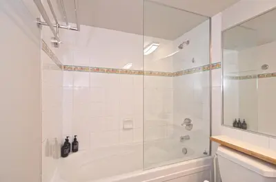 a white bathroom with a tub and a shower at Aspens on the Mountain Ski In Out in Whistler