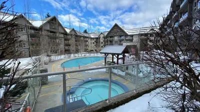 a large apartment building with a swimming pool at Aspens on the Mountain Ski In Out in Whistler