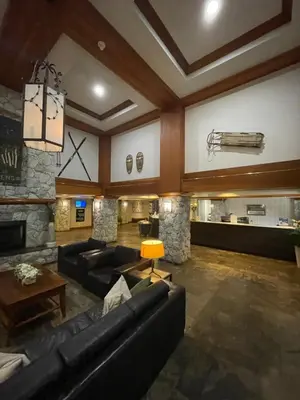 a living room with couches and a stone fireplace at Aspens on the Mountain Ski In Out in Whistler