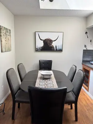 a dining room table with chairs and a bull painting on the wall at Radium Villas in Radium Hot Springs