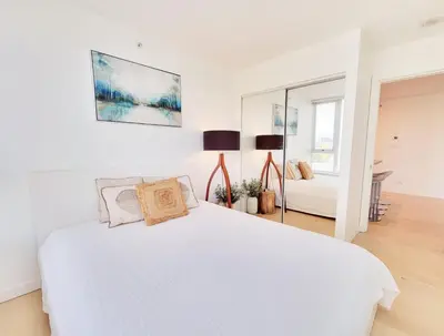 a white bedroom with a bed and a mirror at Beautiful 1 BR in the Heart of Downtown: Parking, Pool & Gym in Vancouver