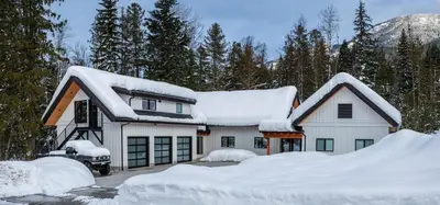 a house covered in snow with a pile of snow at Revelstoke Modern Farmhouse in Revelstoke