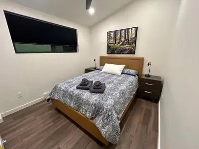 a bedroom with a bed and a flat screen tv at Revelstoke Modern Farmhouse in Revelstoke