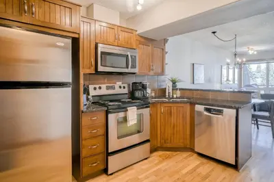 a kitchen with stainless steel appliances and wooden cabinets at Incredible Mountain View Townhouse in DT Canmore w/ A/C & U/A Parking in Canmore