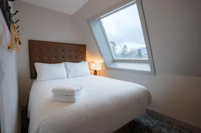 a bedroom with a white bed with a window at Basecamp Suites Banff in Banff