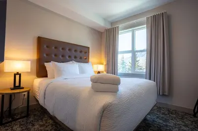 a bedroom with a bed with two lamps and a window at Basecamp Suites Banff in Banff