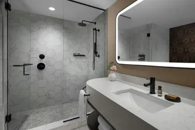 a bathroom with a sink and a shower with a mirror at The Dorian, Autograph Collection in Calgary