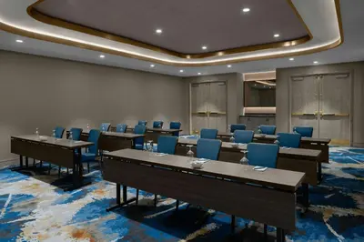 a conference room with tables and blue chairs at The Dorian, Autograph Collection in Calgary