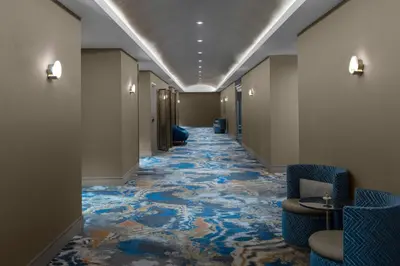 a hallway with blue chairs and a carpet at The Dorian, Autograph Collection in Calgary