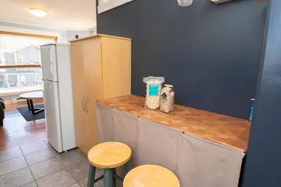 a kitchen with a counter with two stools and a refrigerator at Downtown Whitehorse Apartment in Old Town in Whitehorse