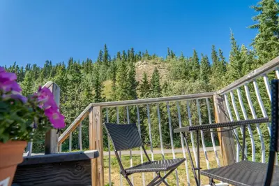 a pair of chairs on a deck with a view of trees at Downtown Whitehorse Apartment in Old Town in Whitehorse