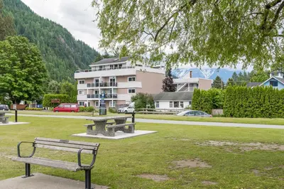 a park with a bench in front of a building at Harrison On The Lake, Walkable to Beach and Village in Harrison Hot Springs