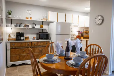 a kitchen with a table with chairs and a refrigerator at Harrison On The Lake, Walkable to Beach and Village in Harrison Hot Springs