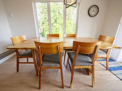 a dining room table with chairs and a clock on the wall at Storm Bay, Family Home with Hot Tub and Inlet View in Ucluelet