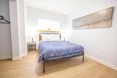 a bedroom with a bed and a painting on the wall at Storm Bay, Modern 1 Bed Suite and Chefs Kitchen in Ucluelet